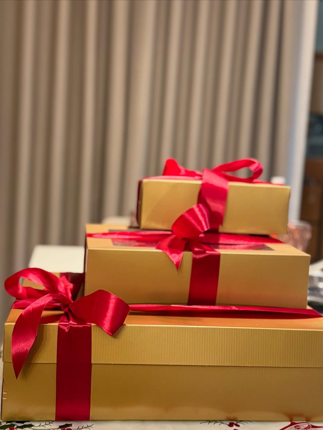 Stacked gold gift boxes with red ribbon bows